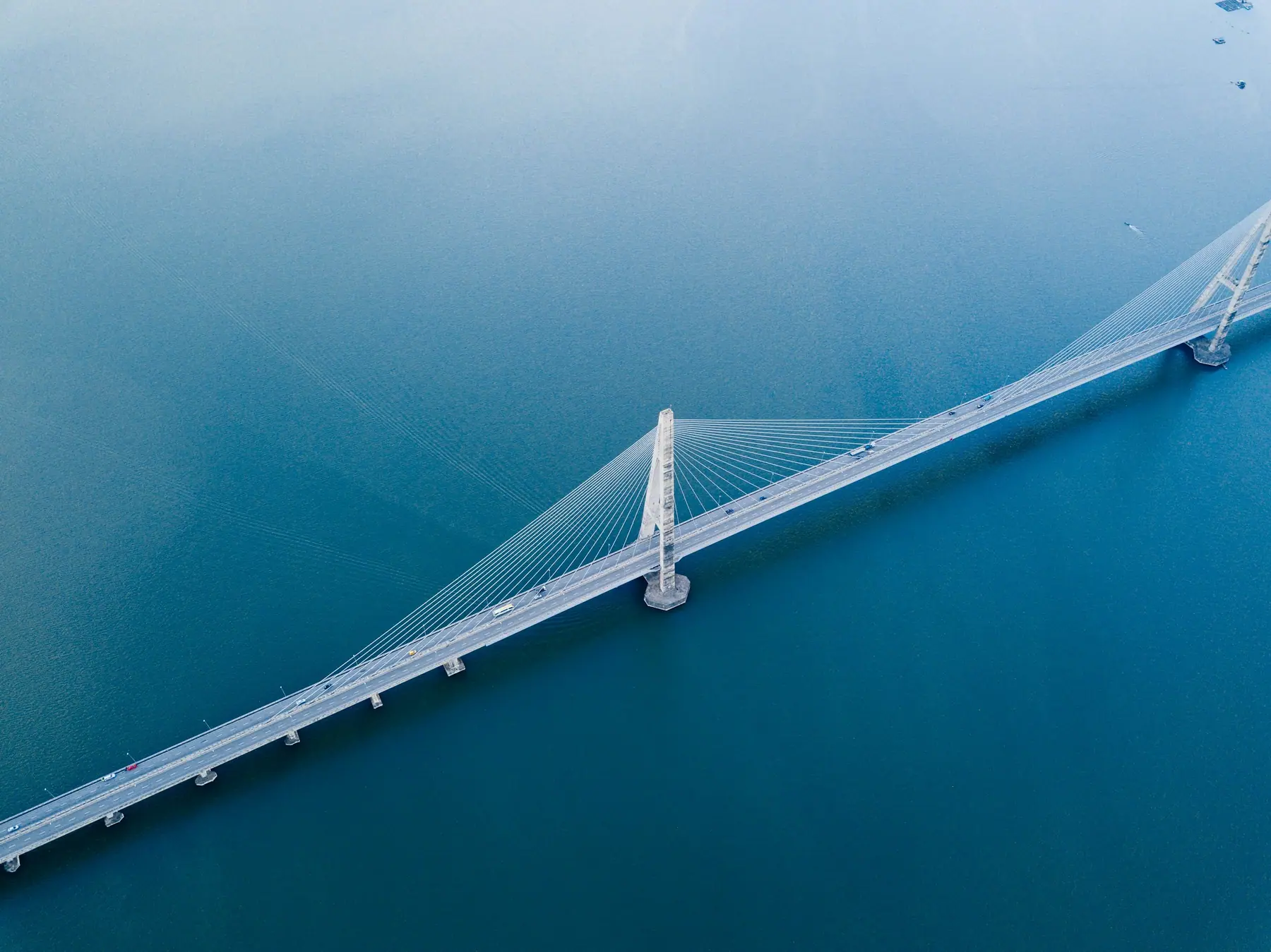 Aerial view of a long bridge crossing deep blue water